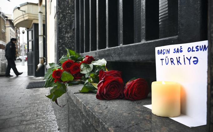 Frente a la embajada de Turquía en Moscú, el 6 de febrero de 2023, se ven flores junto a una vela y un pequeño cartel en el que se lee "Condolencias a Turquía".